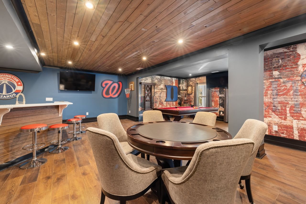Modern basement game room with bar, seating, and pool table.